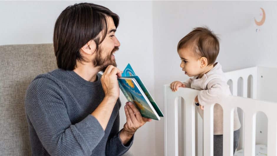 Dad reading book to baby in crib