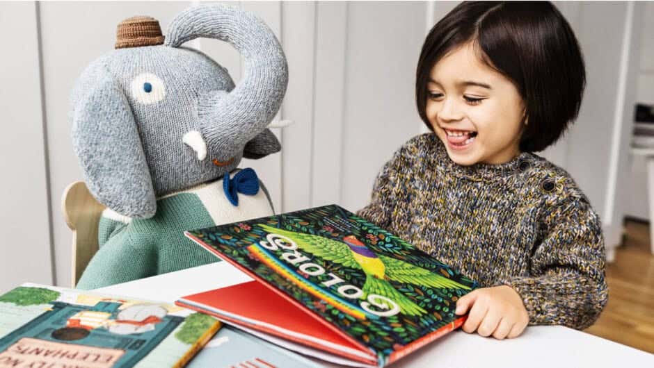 Child reading book with her stuffed elephant