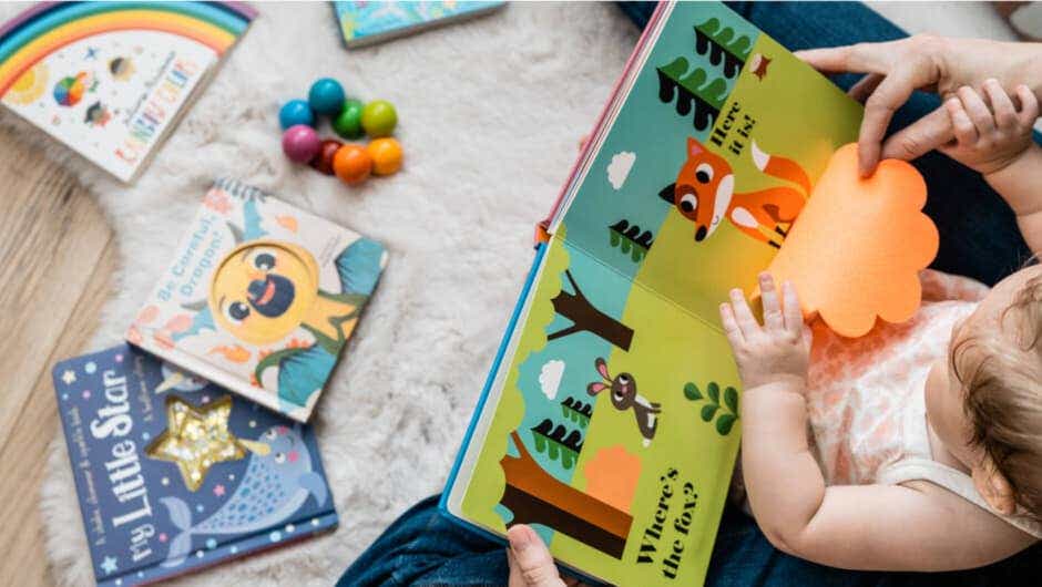 baby reading board books on fluffy rug