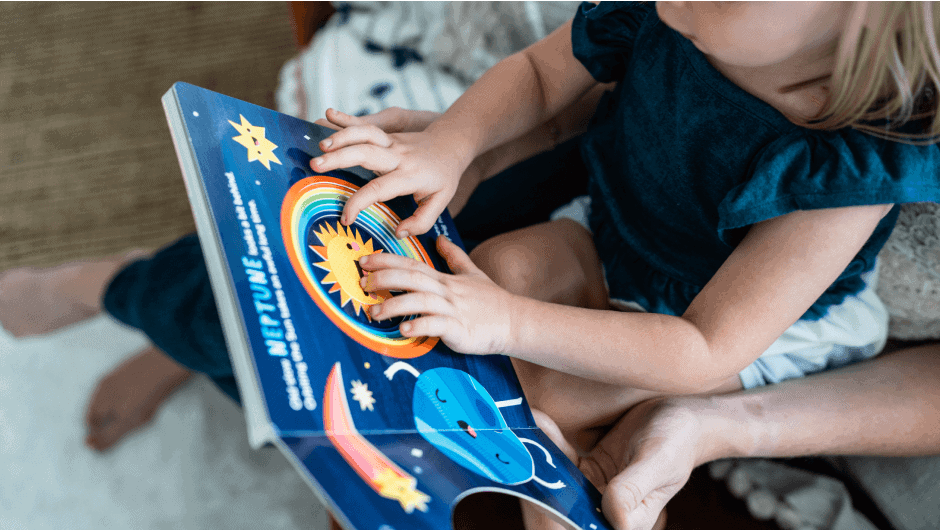 Toddler touching a book about planets