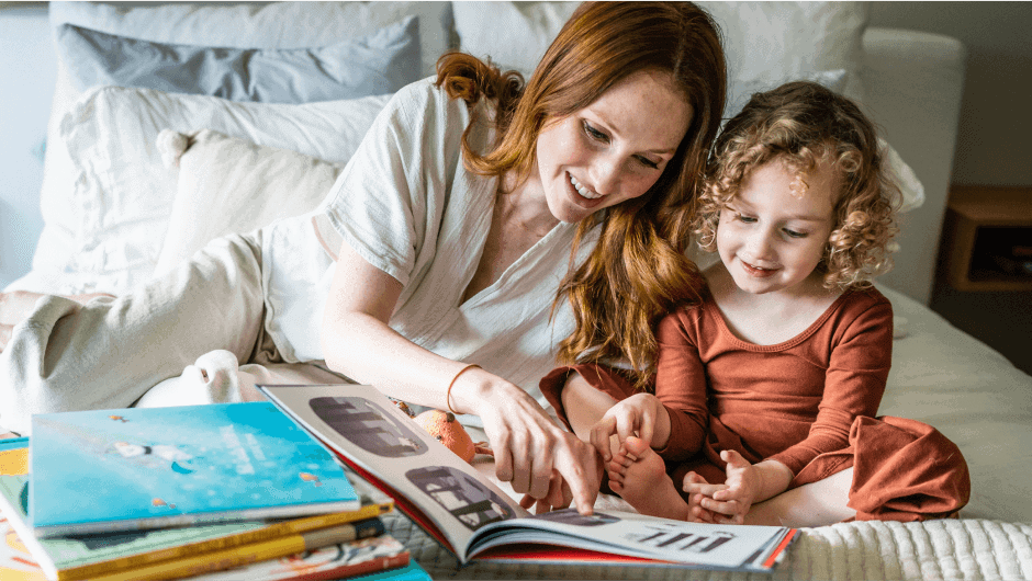Mother reading book to daughter on a bed
